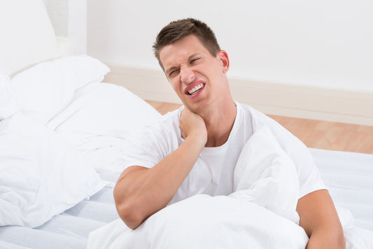 Young man suffering from neckache In bedroom