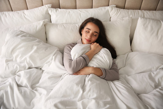 Beautiful young woman wrapped with soft duvet sleeping in bed at home, above view